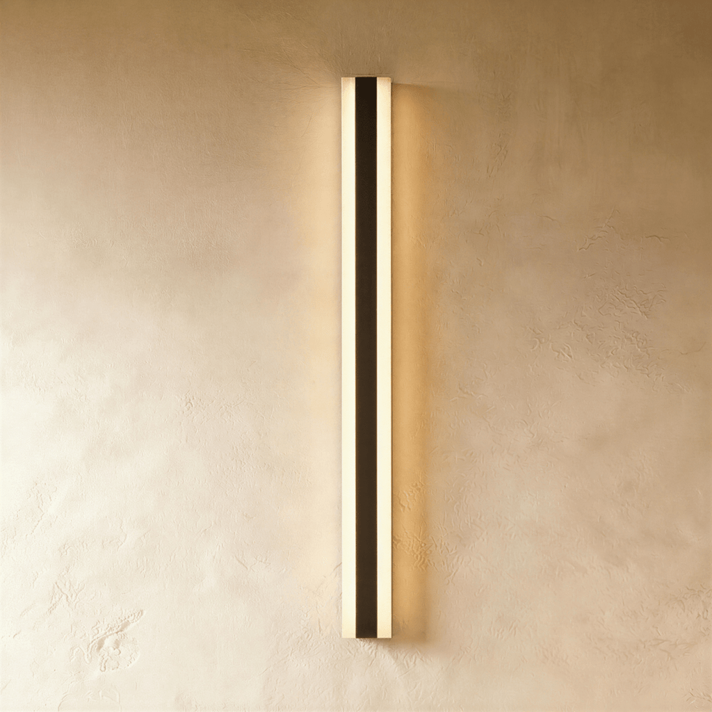 Another studio angle shows the black aluminium column sconce's warm glow spreading evenly across plaster, Clérachic hero shot.