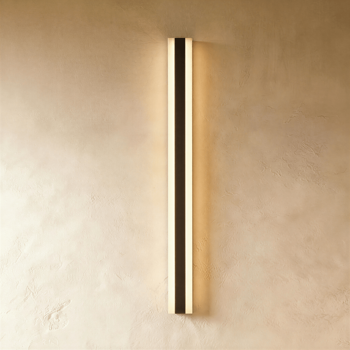 Another studio angle shows the black aluminium column sconce's warm glow spreading evenly across plaster, Clérachic hero shot.