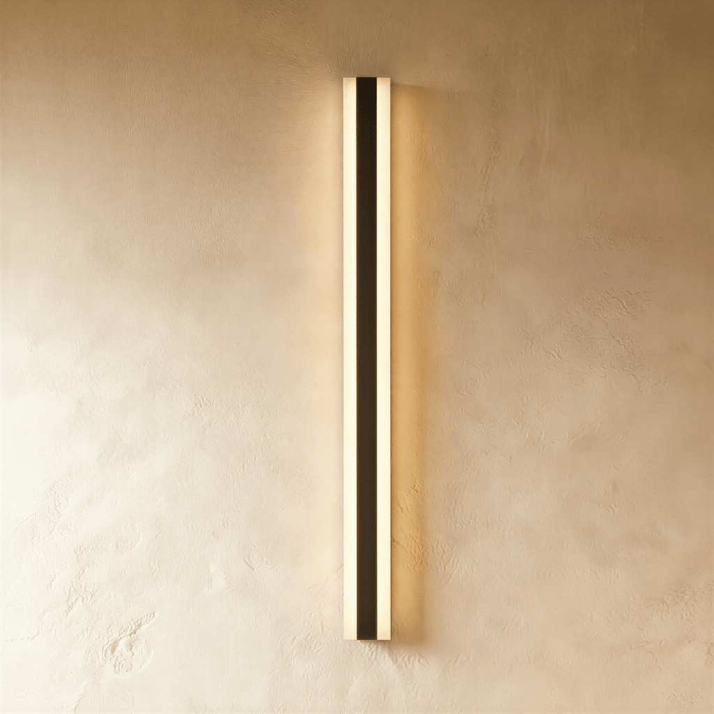 A final studio view of the black aluminium column sconce shows its slim profile glowing warm on plaster, Clérachic hero shot.