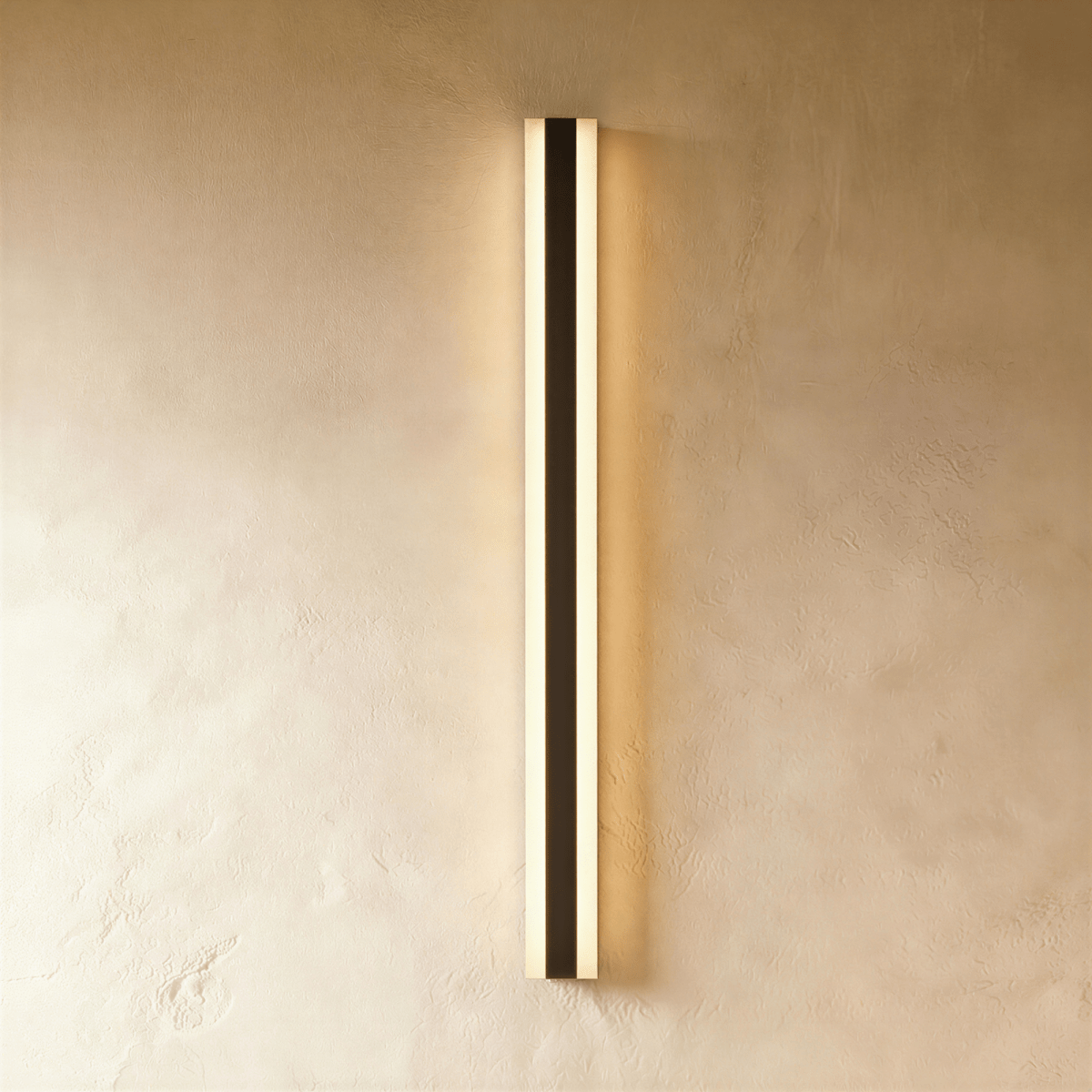 A final studio view of the black aluminium column sconce shows its slim profile glowing warm on plaster, Clérachic hero shot.