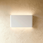 A mid-size white up-down sconce glows evenly above and below its rectangular body, Clérachic hero shot.