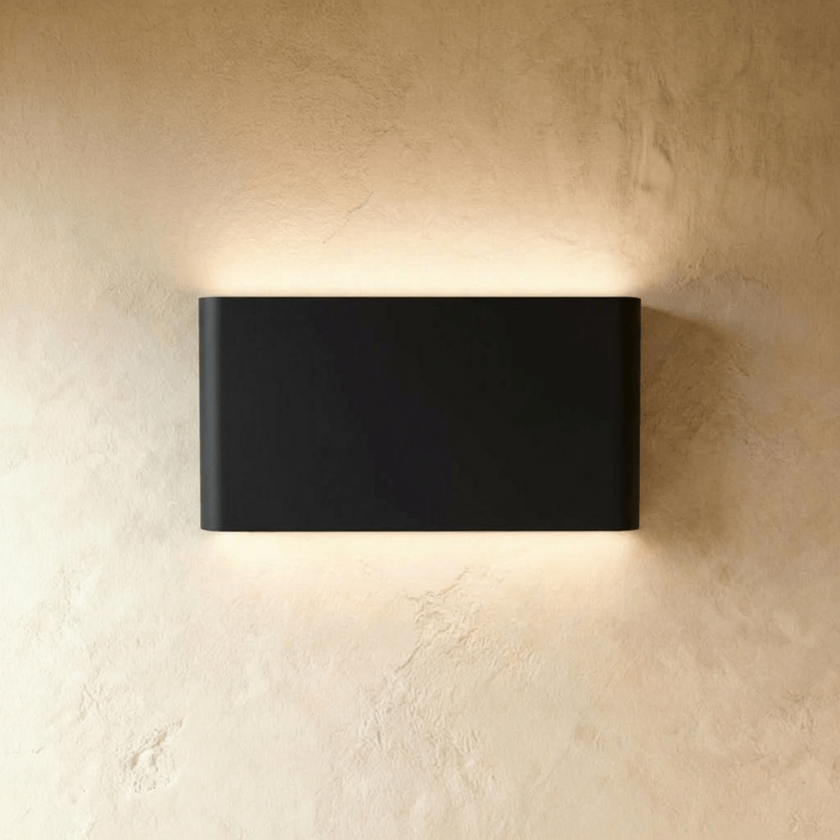 A mid-size black up-down sconce lights a wide band of plaster wall from its rectangular body, Clérachic hero shot.