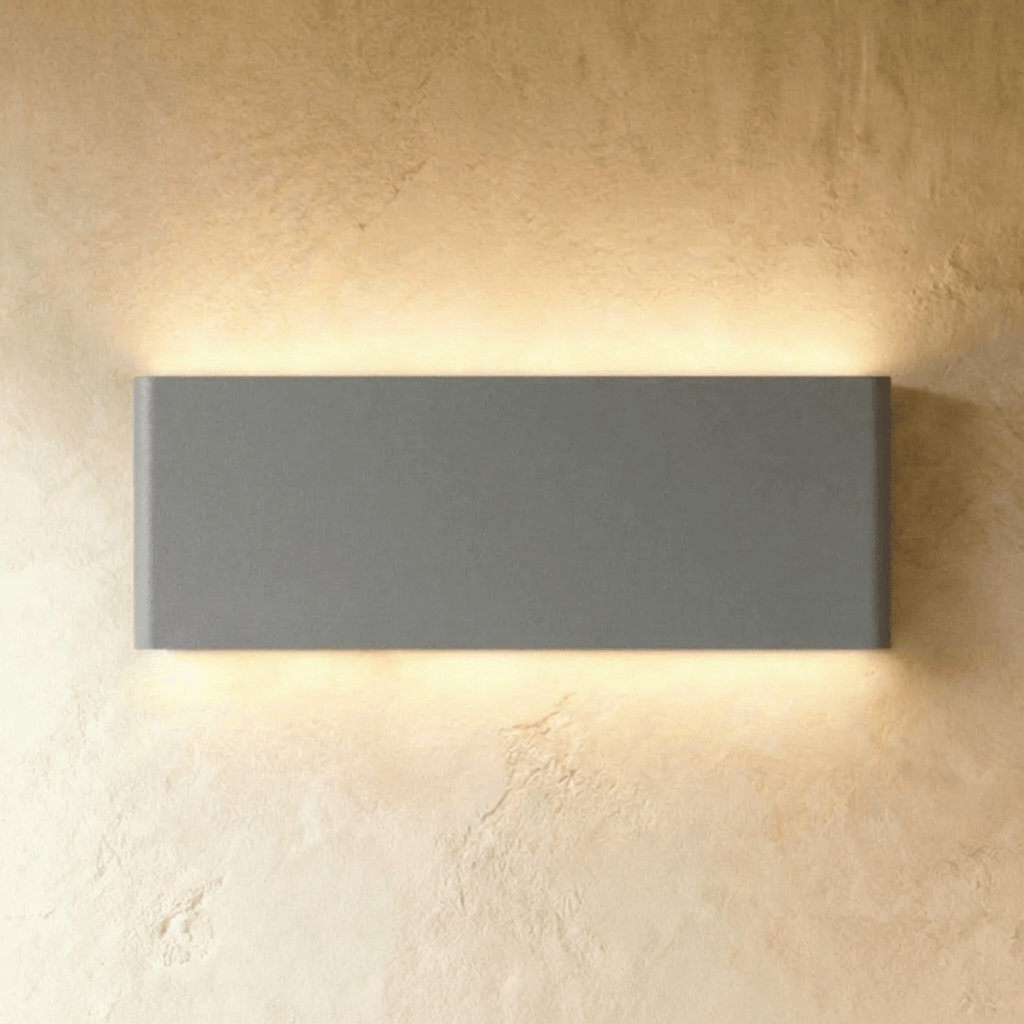 The largest grey up-down sconce spans a broad rectangular body, glowing warm top and bottom, Clérachic hero shot.