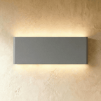 The largest grey up-down sconce spans a broad rectangular body, glowing warm top and bottom, Clérachic hero shot.