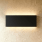 The largest black up-down sconce casts an even warm glow from its long rectangular body, Clérachic hero shot.