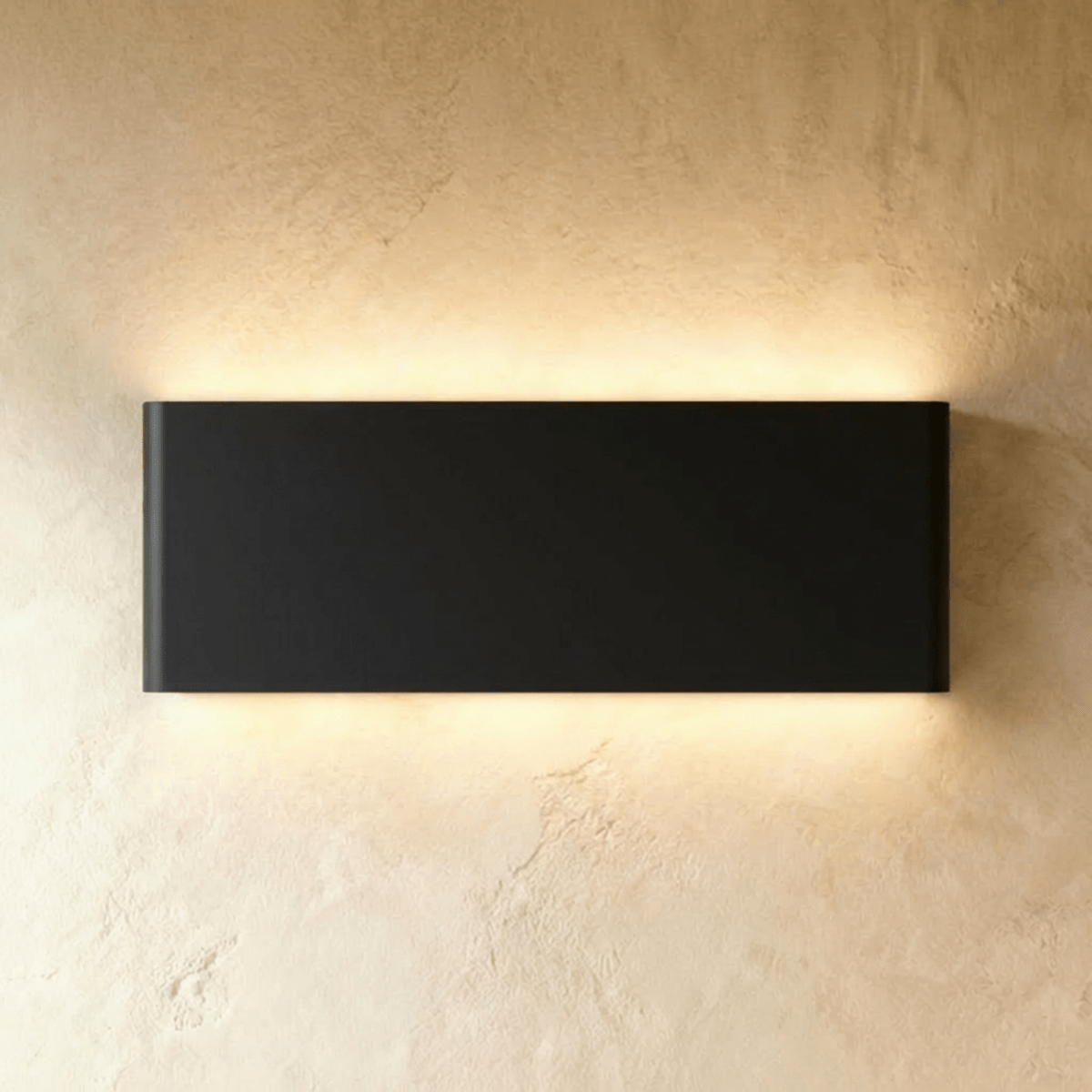 The largest black up-down sconce casts an even warm glow from its long rectangular body, Clérachic hero shot.