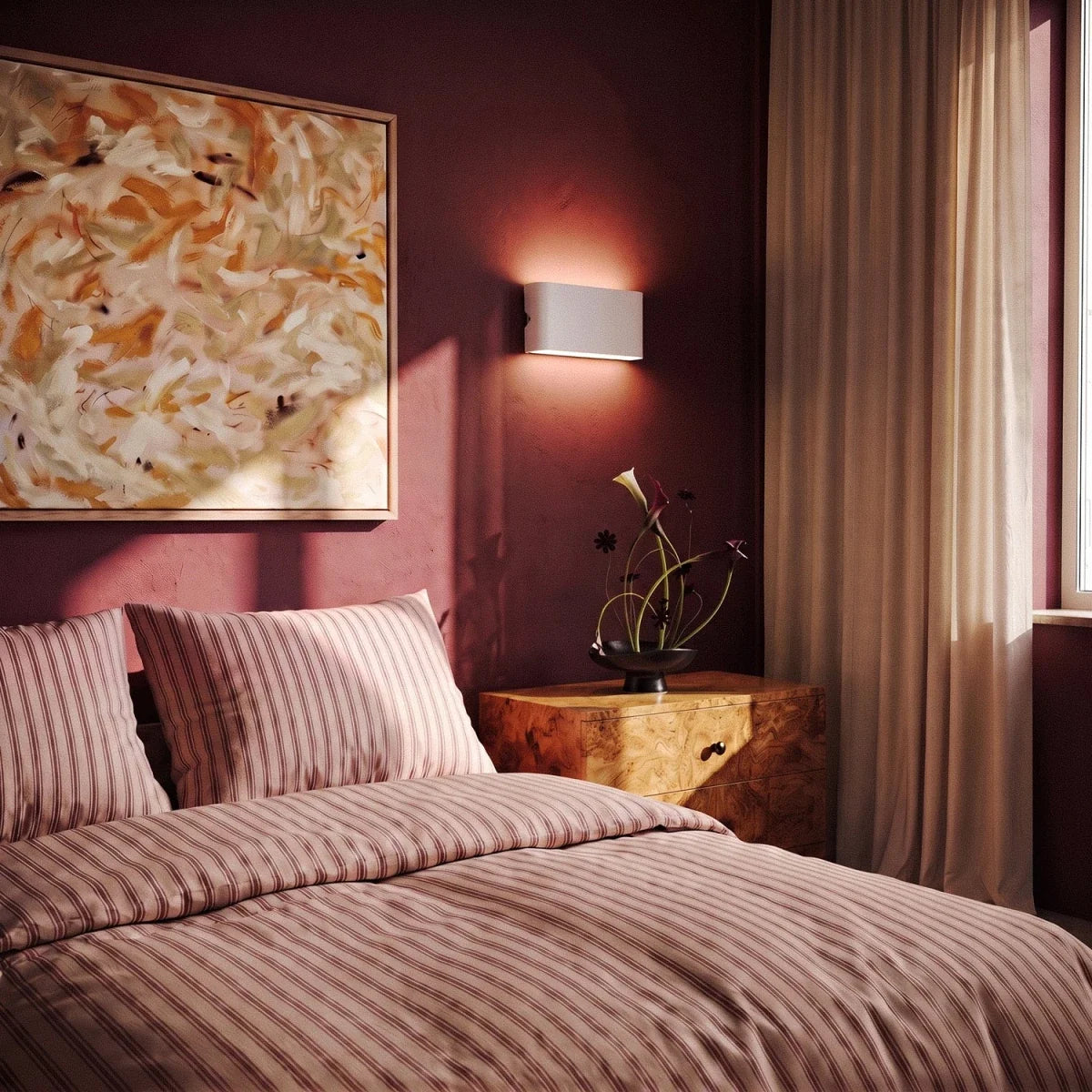 A white up-down sconce glows above a burl-wood nightstand in a deep-rose bedroom with striped bedding, Clérachic lifestyle shot.