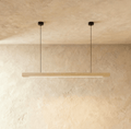 Clérachic's pine wood pendant bar hangs from two round black ceiling canopies against a plaster wall.