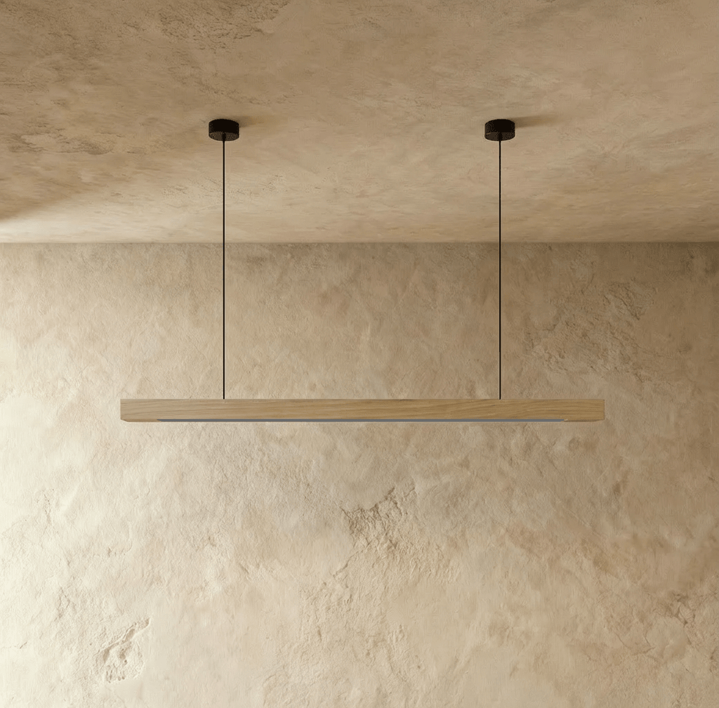 This Clérachic pine pendant light bar glows softly, suspended from twin round black ceiling mounts.