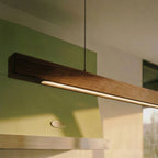 This close angle shows the Clérachic pendant bar's black walnut grain and LED edge above a green range.