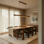 A Clérachic black walnut pendant bar lights a dining table with olive velvet chairs and abstract art.