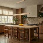 A Clérachic pine pendant bar hangs above a rustic kitchen island with woven stools and a lemon bowl.