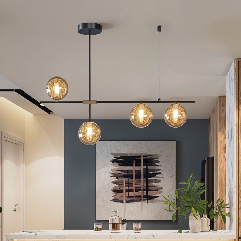 Clérachic 4-head chandelier with amber globes on a black bar above a marble counter and a blue-grey feature wall.