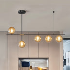 Clérachic 5-head chandelier with amber globes on a black bar in a kitchen with taupe cabinetry and a lit shelf.