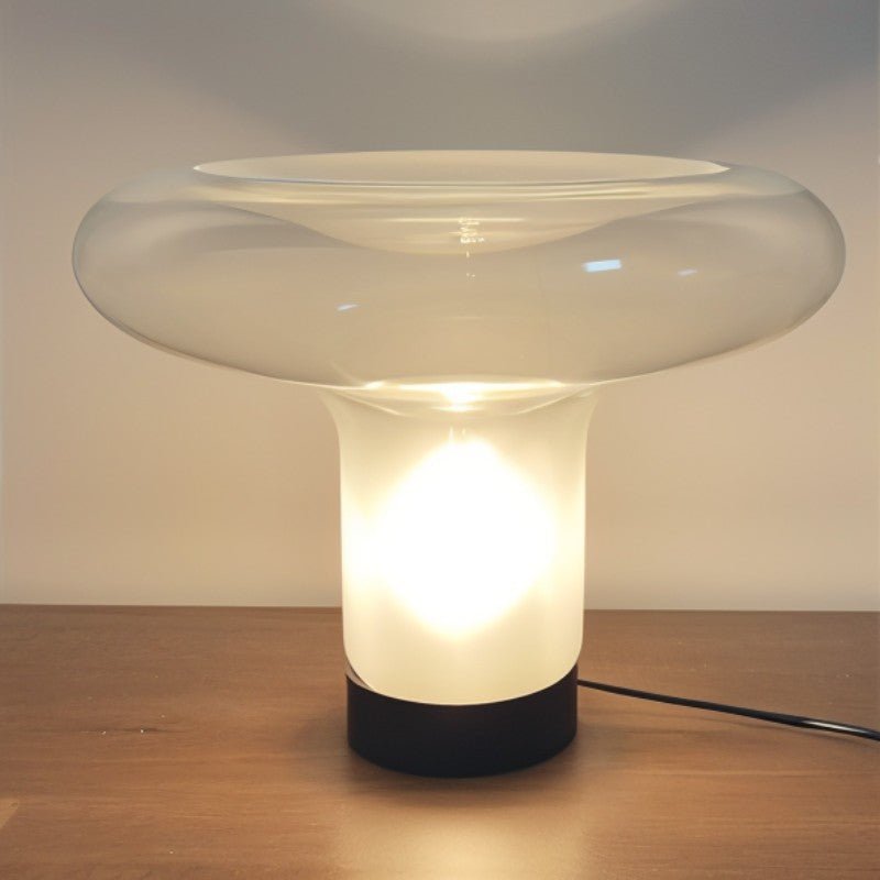 Clérachic mushroom glass table lamp, 43 cm across, lit warm on a wooden surface with its black cable running to the right.