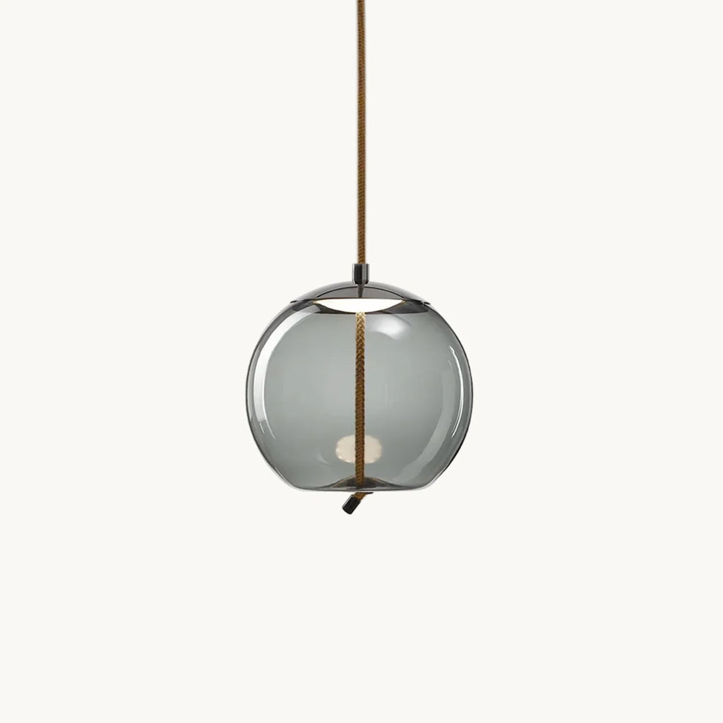 A round smoke-grey glass Clérachic pendant hangs from a braided rope cord on a plain white backdrop, with a small light visible inside.