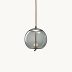 A round smoke-grey glass Clérachic pendant hangs from a braided rope cord on a plain white backdrop, with a small light visible inside.