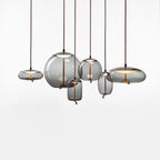 On a white backdrop, six smoke-grey glass Clérachic pendants in round, flat and tall shapes hang at different heights from braided cords.