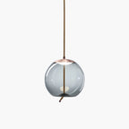 A round smoke-grey glass Clérachic pendant with a copper-toned cap hangs from a braided cord on a plain white backdrop.