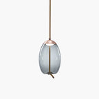 A narrow oval smoke-grey glass Clérachic pendant with a copper-toned cap hangs from a braided cord on a pale backdrop.