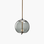 A round smoke-grey glass Clérachic pendant with a dark metal cap and a looped rope tail hangs on a pale backdrop.