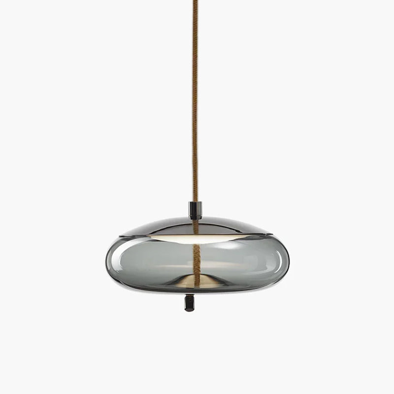 A wide, flat smoke-grey glass Clérachic pendant with a dark metal top hangs from a brown braided cord on a pale backdrop.