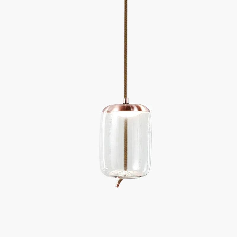 A tall clear glass Clérachic pendant with a copper-toned cap and a rope tail hangs on a pale backdrop.