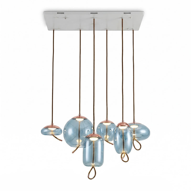 Six aqua-blue glass Clérachic pendants in round, flat and tall shapes hang from one long white ceiling plate on a pale backdrop.