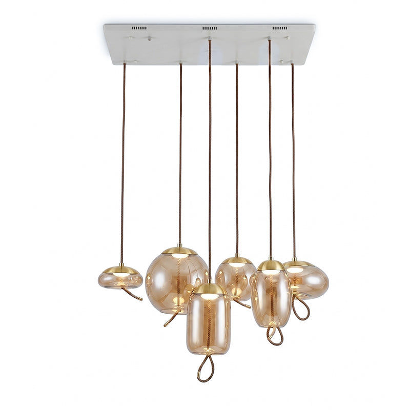 Six amber glass Clérachic pendants in mixed shapes hang from one rectangular white ceiling plate, each with a small warm light.