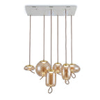 Six amber glass Clérachic pendants in mixed shapes hang from one rectangular white ceiling plate, each with a small warm light.