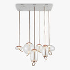 Six clear glass Clérachic pendants with copper-toned caps hang from one long white ceiling plate, in round, flat and tall shapes.