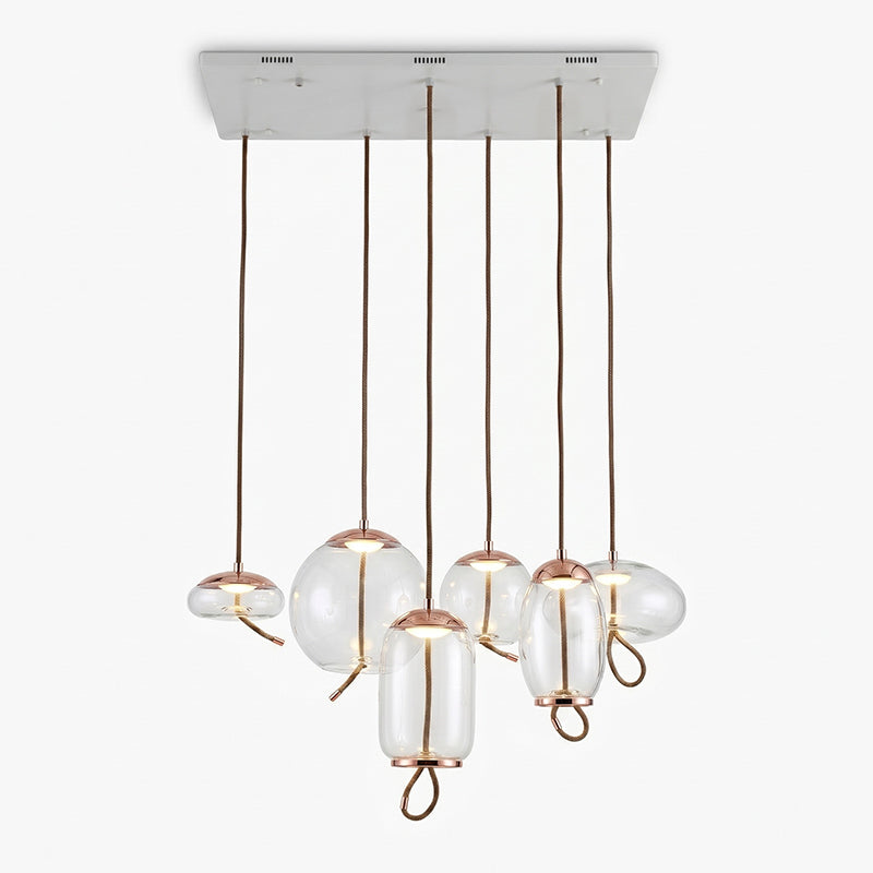 Six clear glass Clérachic pendants with copper-toned caps hang from one long white ceiling plate, in round, flat and tall shapes.