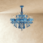 Clérachic blue glass chandelier with two tiers of candle bulbs and hanging crystal drops on a plaster backdrop
