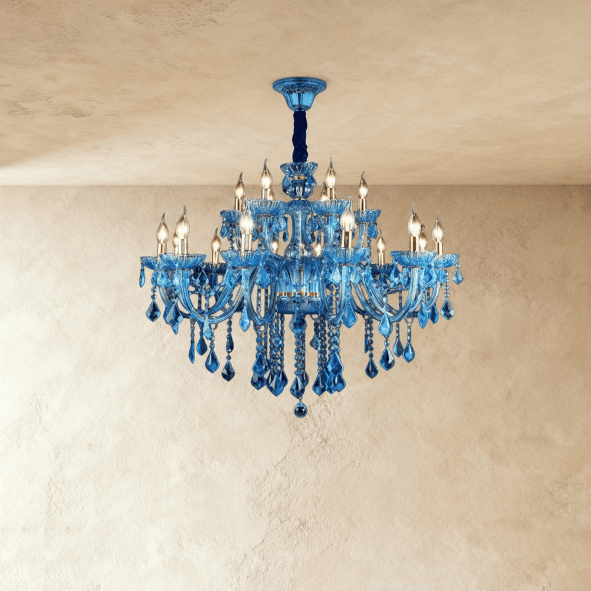 Clérachic blue glass chandelier with two tiers of candle bulbs and hanging crystal drops on a plaster backdrop