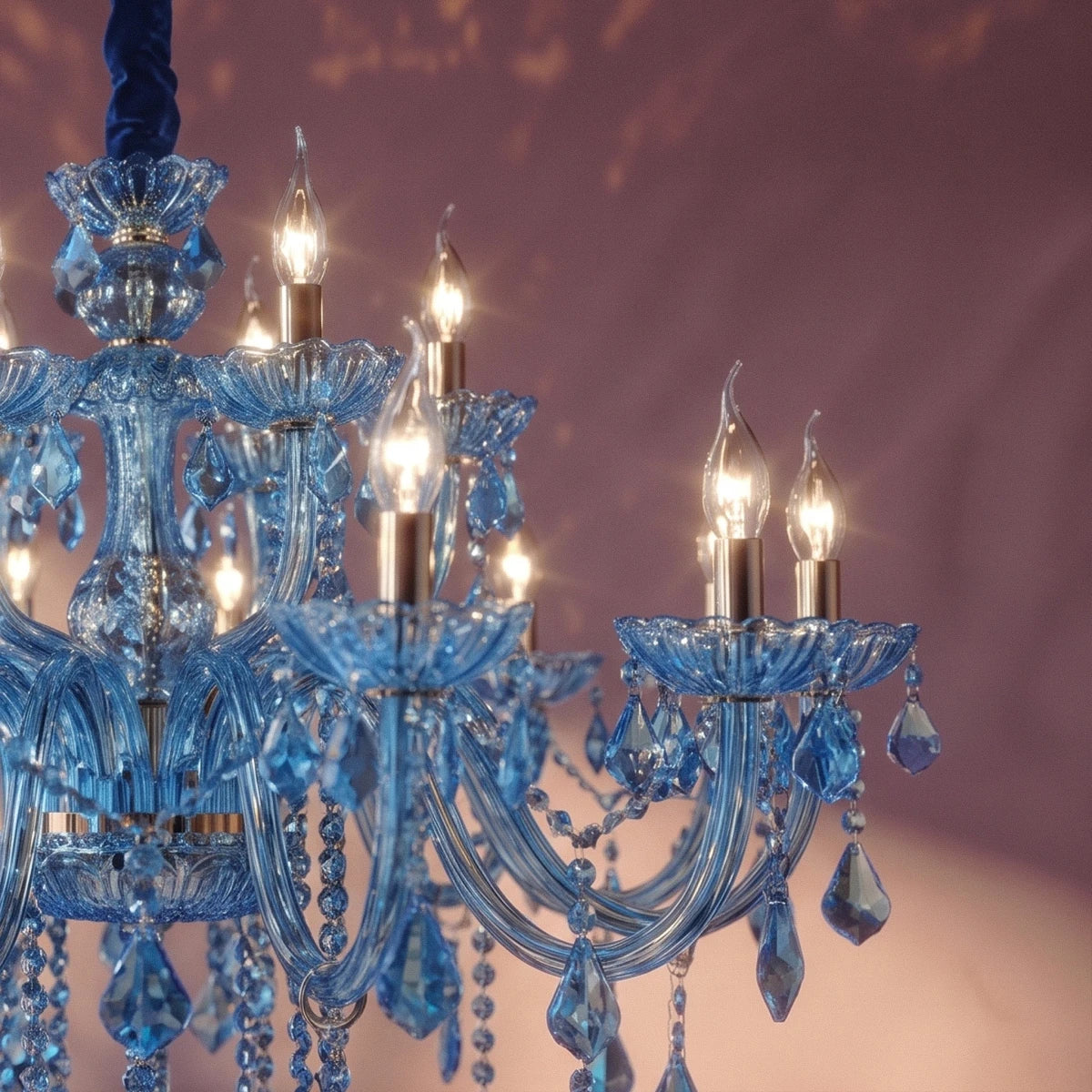 Close view of Clérachic blue glass arms, cut-glass cups and warm candle bulbs against a plum wall