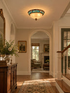Clérachic ceiling light glowing over a hallway with an arched doorway, a wood chest and a vase of white flowers.