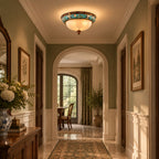 Clérachic ceiling light above a sage-green corridor with a patterned runner, an arch and a vase of white hydrangeas.