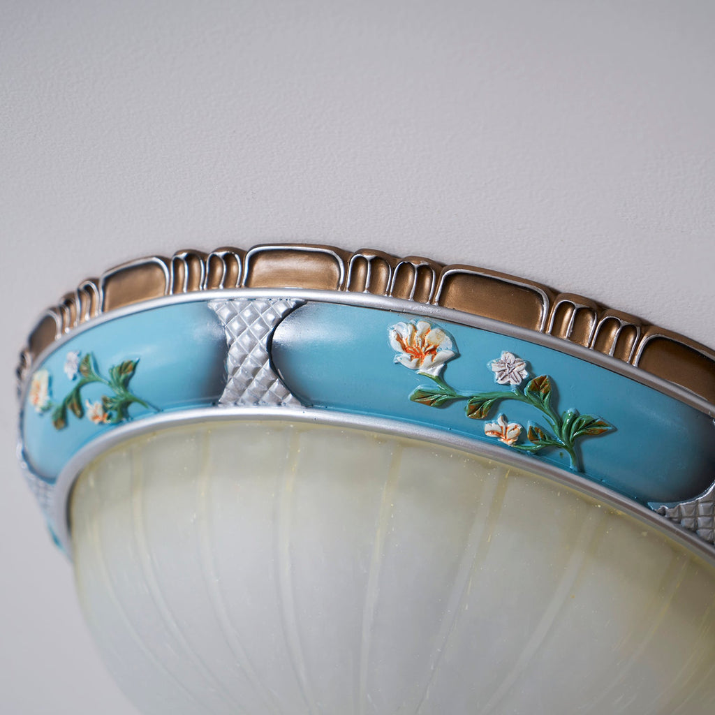 Close view of the turquoise resin band on this Clérachic ceiling light, with painted flowers, silver lattice panels and a brown rim.