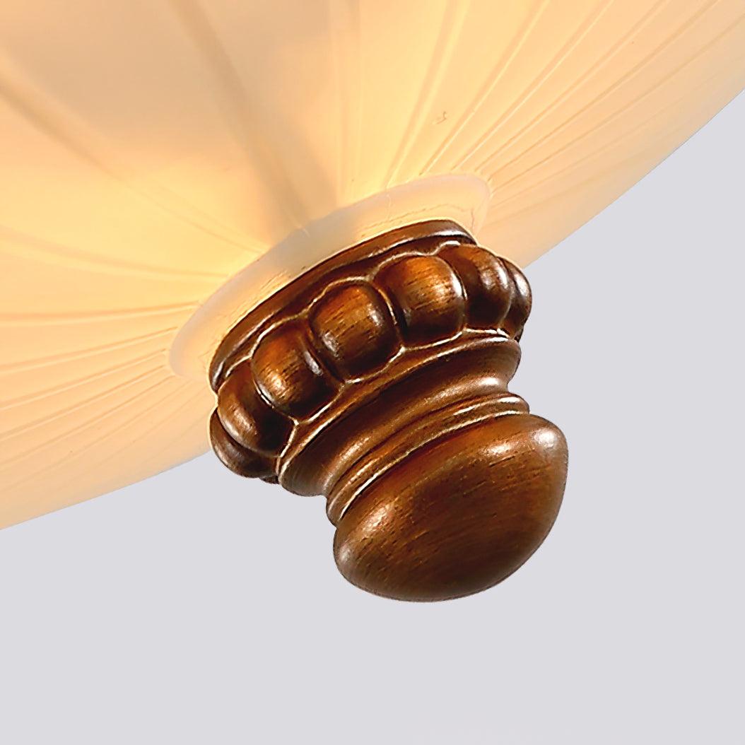 Looking up at the brown turned finial under the glowing glass bowl of this Clérachic ceiling light.