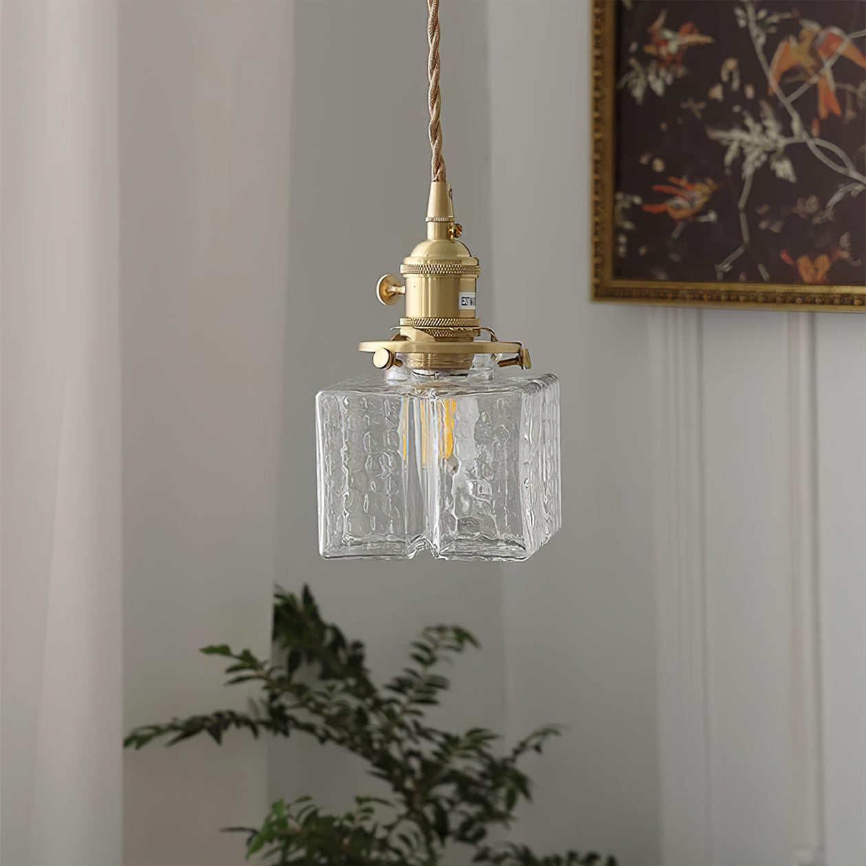 Clérachic boxy hammered-glass pendant light, Model A, hanging solo against a pale curtain with potted greenery below.