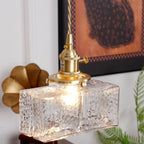 Close-up of a lit Clérachic boxy hammered-glass pendant light in Model A size, filament glowing through the rippled glass.