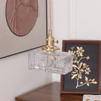 Clérachic boxy hammered-glass pendant light, Model B, lit above a walnut console beside a framed gold botanical print.