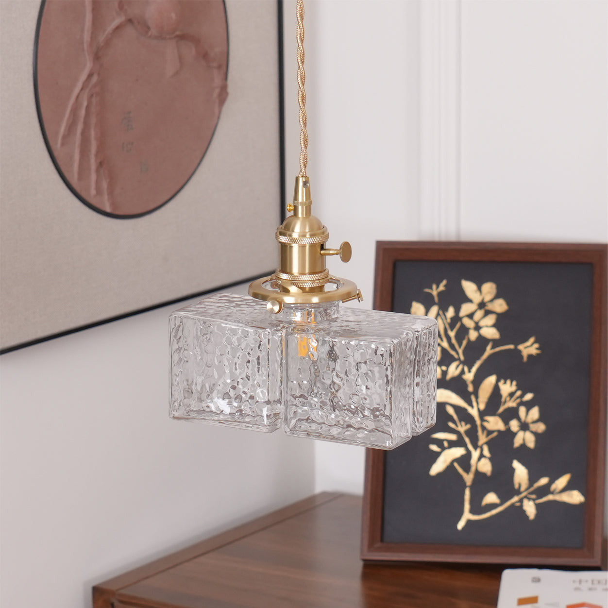 Clérachic boxy hammered-glass pendant light, Model B, lit above a walnut console beside a framed gold botanical print.