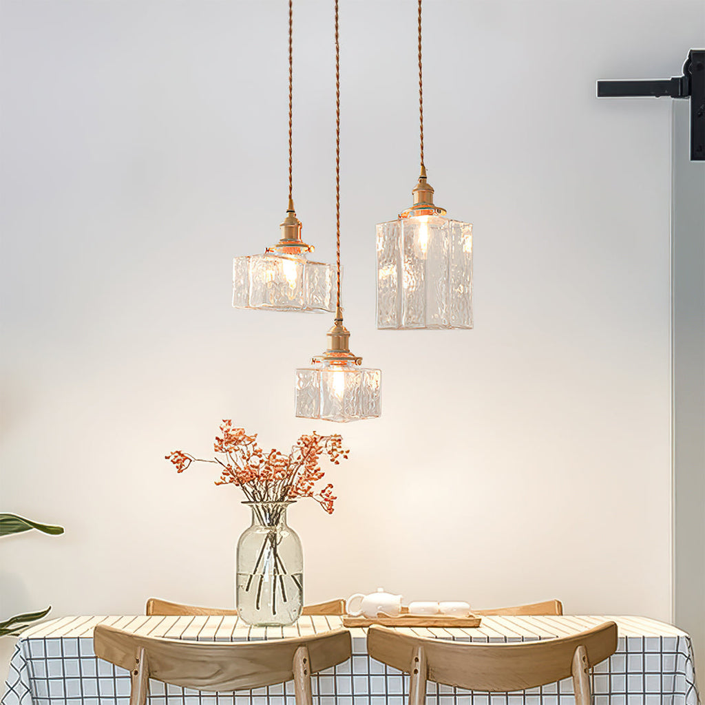 Three Clérachic boxy hammered-glass pendant lights, two Model B and one Model C, clustered above a breakfast table set for tea.
