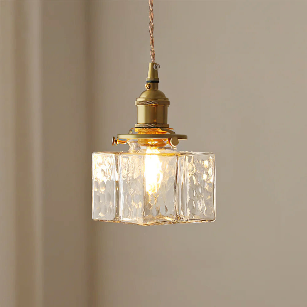 Clérachic boxy hammered-glass pendant light, Model B, lit and hanging against a plain warm taupe wall.