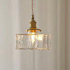 Clérachic boxy hammered-glass pendant light, Model B, lit against a soft pleated curtain backdrop.