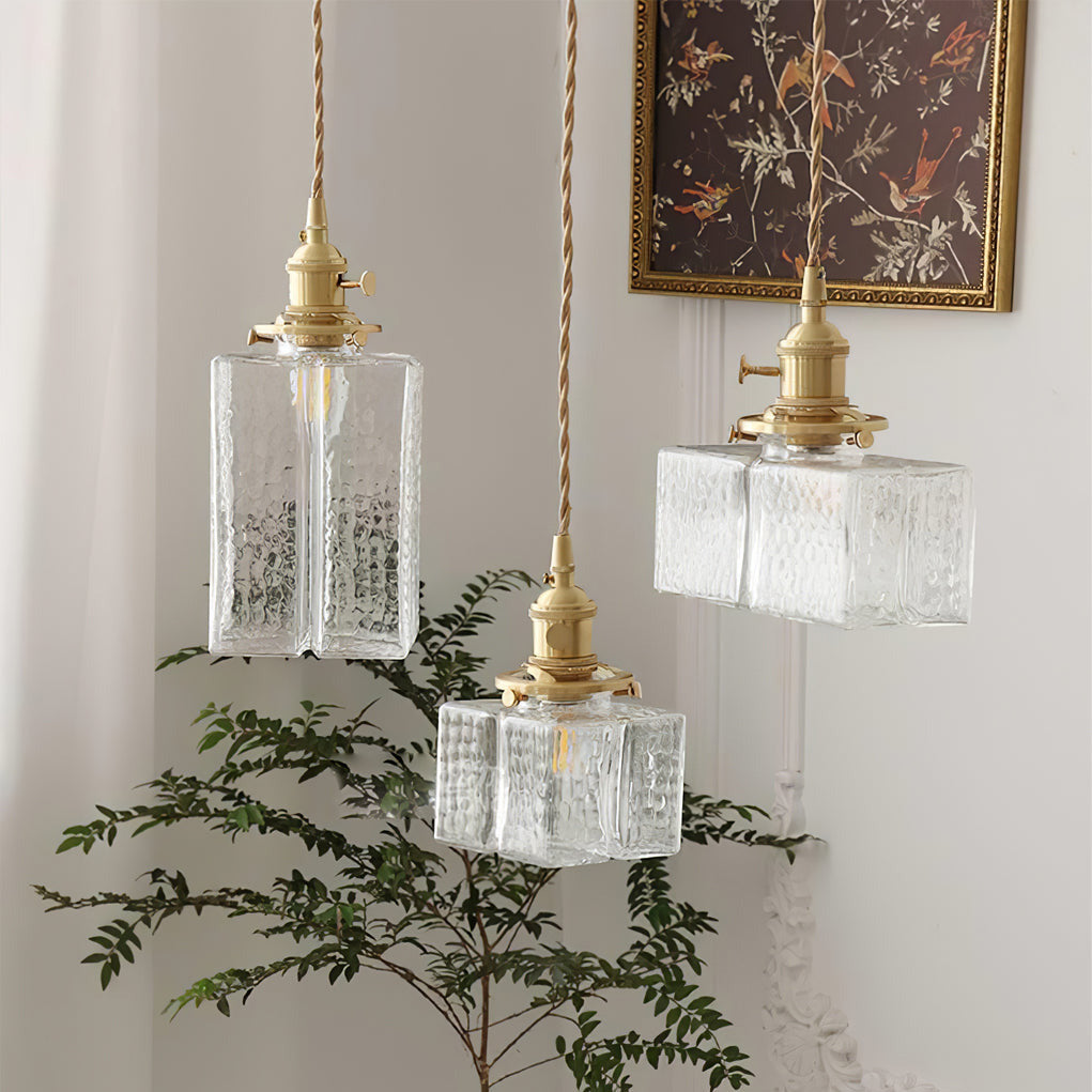 All three Clérachic boxy hammered-glass pendant light shapes lit together beside a leafy plant and framed bird artwork.