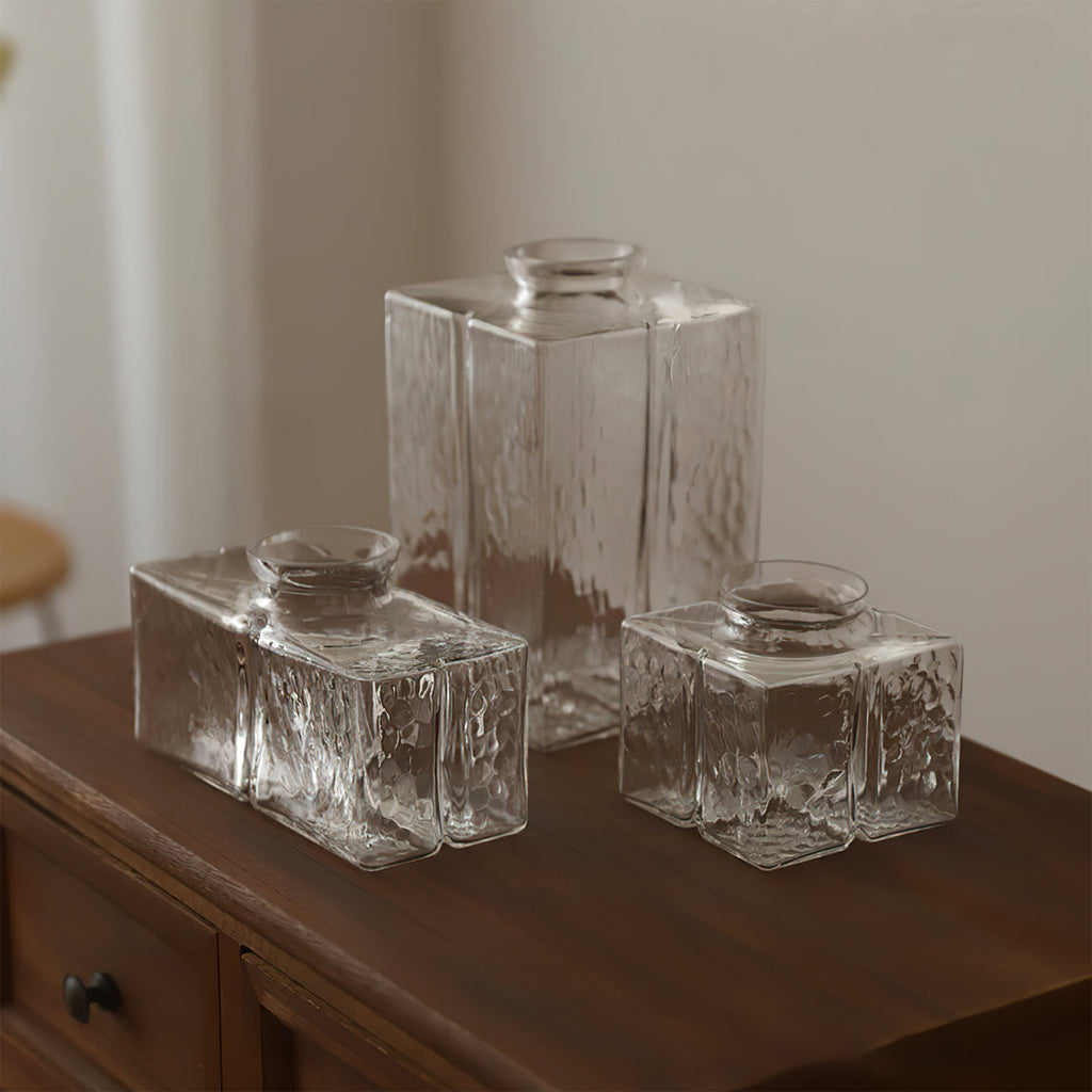 The three hammered-glass shades of the Clérachic boxy pendant light standing bare on a wood dresser, showing the glass texture.