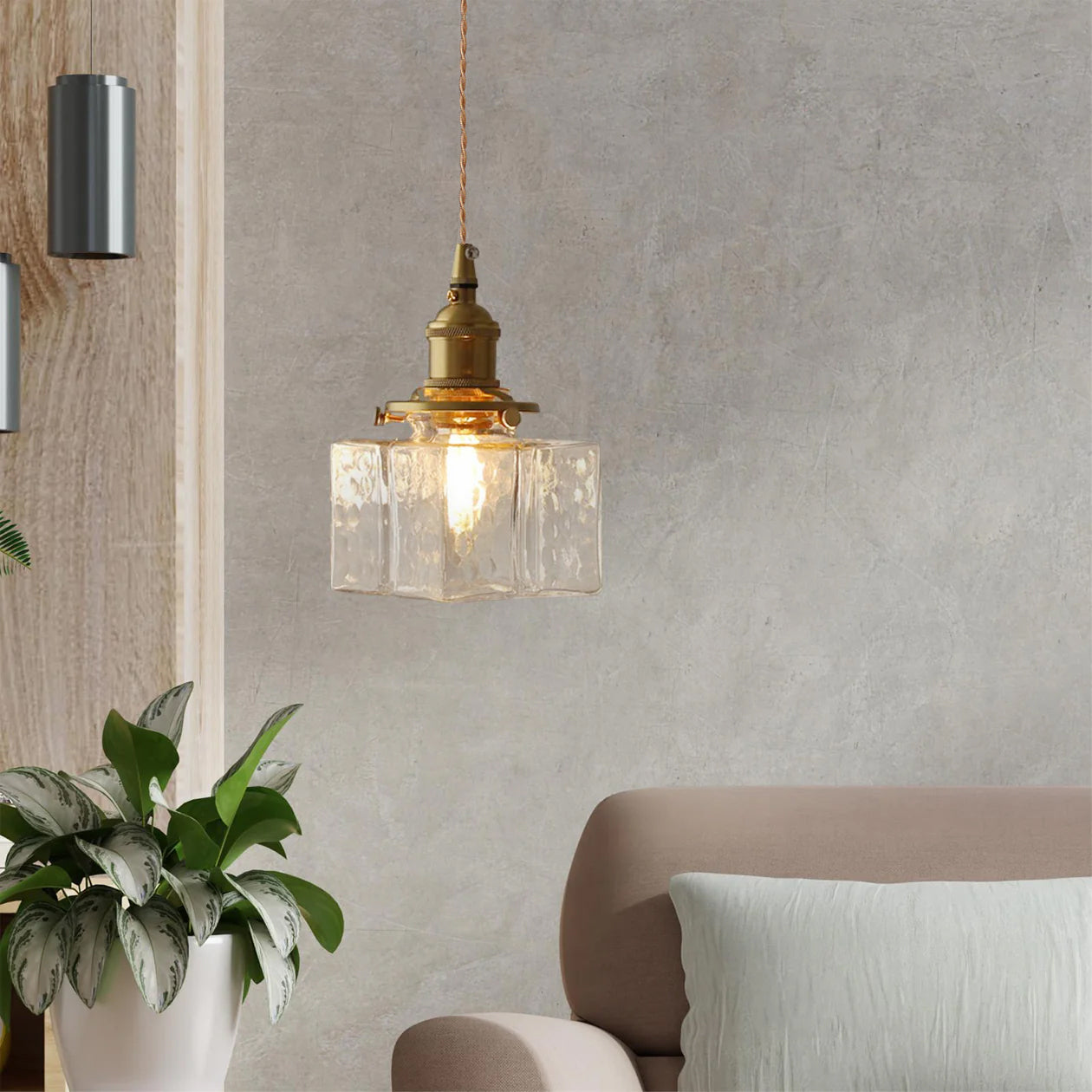 Clérachic boxy hammered-glass pendant light, Model A, lit in a living room with a textured wall and potted plant.