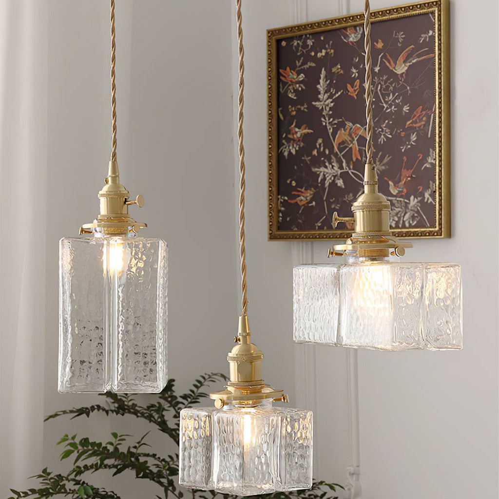 All three Clérachic boxy hammered-glass pendant light shapes lit near a gold-framed floral print and a potted fern.